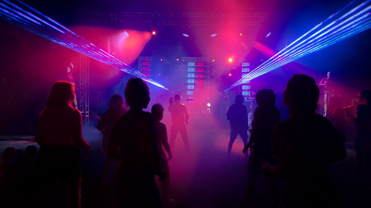 Silhouettes on a dance floor beneath colourful laser lights