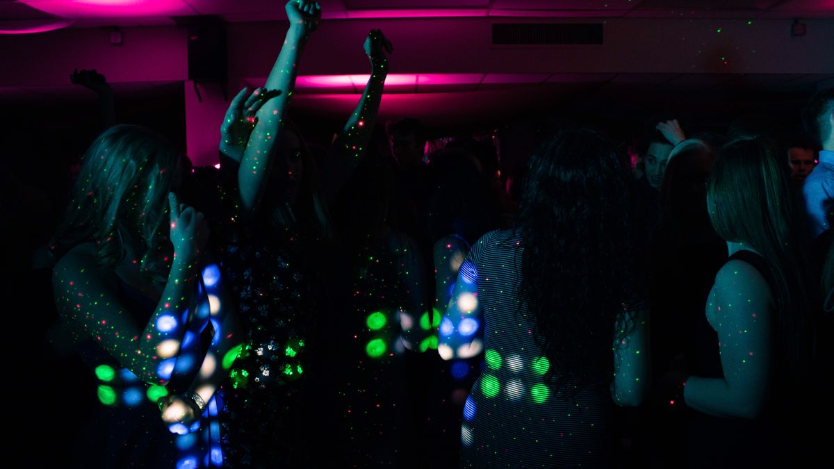 A nightclub crowd dancing under bright coloured lights